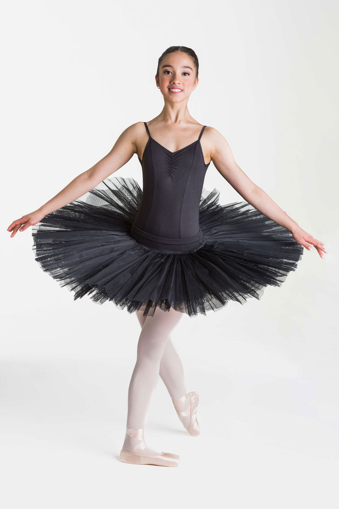 Ballerina in a black tutu posing on a white background